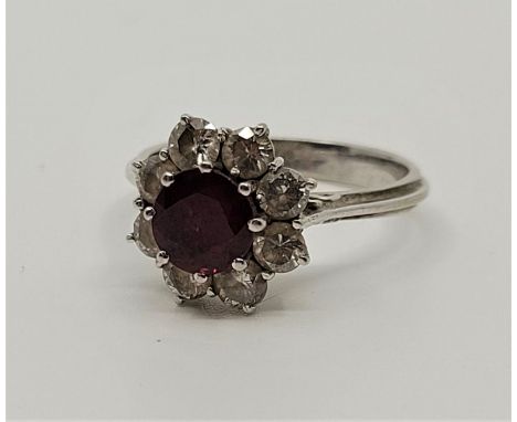 An 18ct. white gold, diamond and ruby ring, set round mixed cut ruby to raised centre, bordered by eight round brilliant cut 