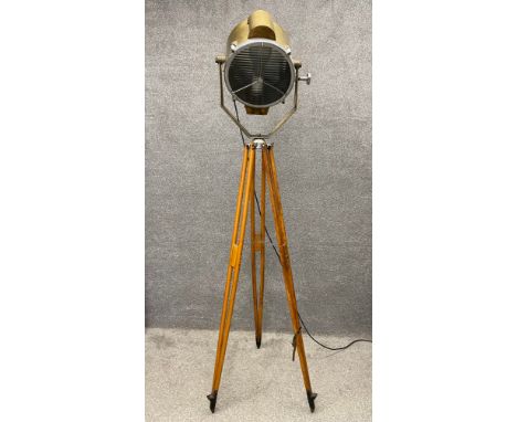 An early to mid 20th century brass floor standing spot lamp on adjustable teak tripod supports. H.207cm.
