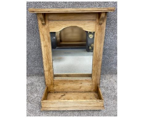 A pine wall mounted mirror with a moulded and bracketed cornice above a shaped frieze framing the mirror plate which sits abo