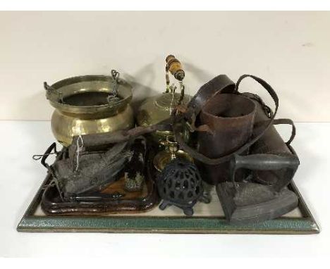 A tray of brass hanging planter and kettle, hearth brush, scoop, flat irons, leather flask holder etc 