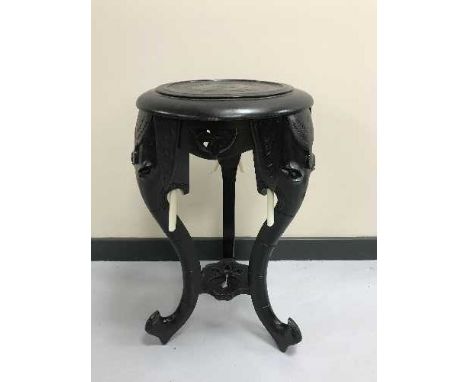 An ebonised plant stand with elephant trunk supports 