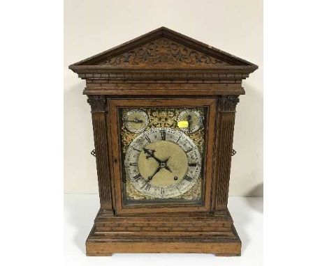 An oak cased quarter-striking table clock, the carved case with architectural pediment and pierced sound-frets, the brass and