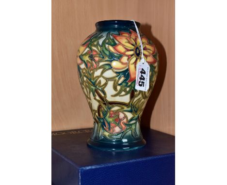 A BOXED MOORCROFT POTTERY 'SPIKE' BALUSTER VASE, having tube lined orange and yellow flowers with spiky green foliage on a bl