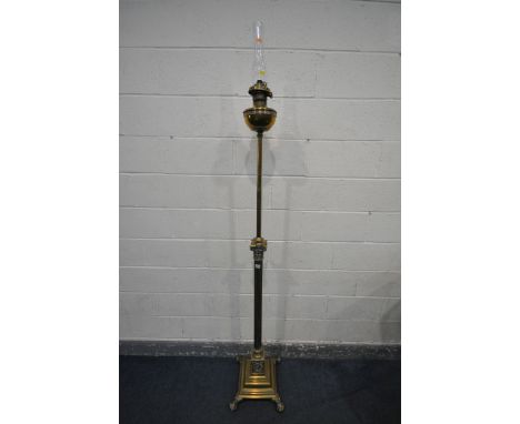 A BRASS FLOOR STANDING TELESCOPIC CORINTHIAN COLUMN OIL LAMP, on a stepped base with claw feet, and a glass chimney shade, th
