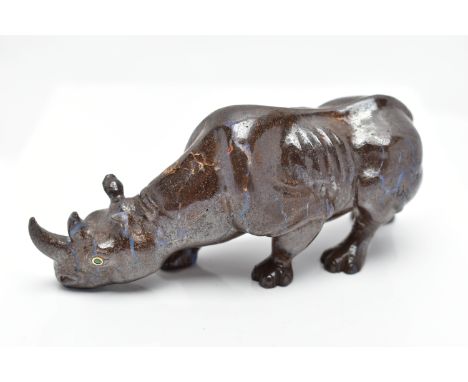 A CARVED BOULDER OPAL RHINO, the figure designed as a rhino, carved from boulder opal, with green garnet eyes, approximate di