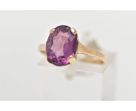 A YELLOW METAL AMETHYST RING, an oval cut amethyst four claw set in a yellow metal mount, polished band stamped 9ct, ring siz