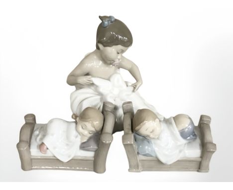 A Nao figure of a baby girl 1337, and two further children figures in bed