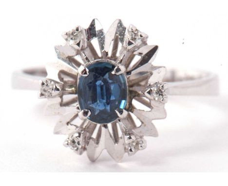 A modern 18ct white gold diamond and blue stone ring, the centre stone surrounded by six small single cut diamonds in an illu