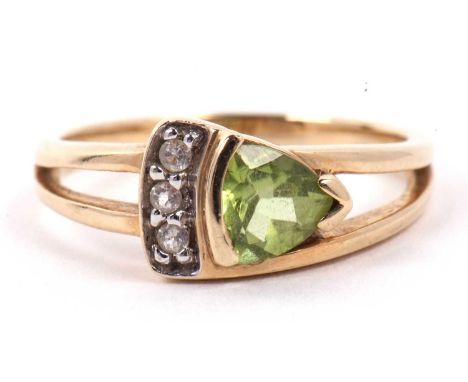 A modern 9ct gold peridot and diamond ring, the shield shaped faceted peridot is highlighted beside with three small diamonds