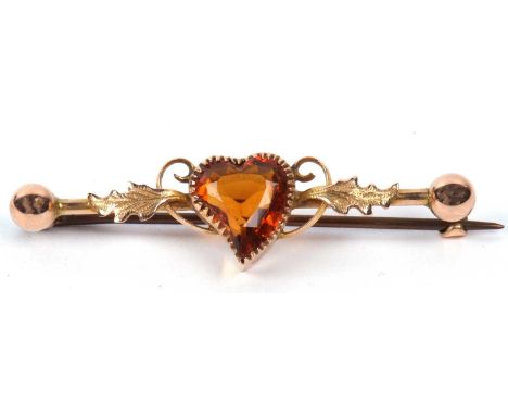 A vintage citrine set brooch, the heart shaped cognac coloured citrine raised between engraved leaves and ball finial termina