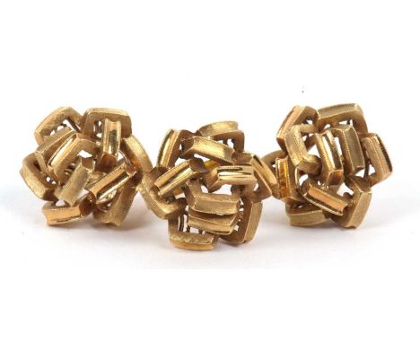 A large stylised ring, a design with plain and textured links in a knot design to a plain shank, stamped 18k, size K together