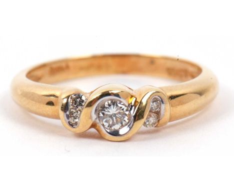 A three stone diamond ring, the bezel set centre stone with a brilliant cut diamond flanked by four small diamonds, stamped 1
