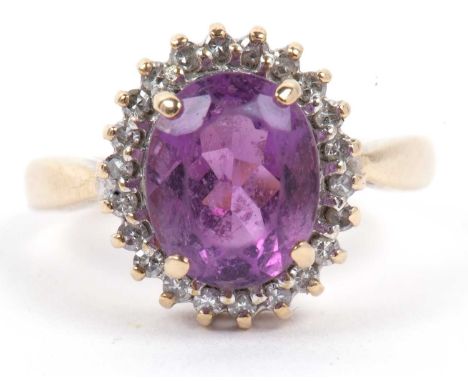 A 9ct gold amethyst and diamond cluster ring, the oval faceted amethyst raised above a small single cut diamond surround, siz