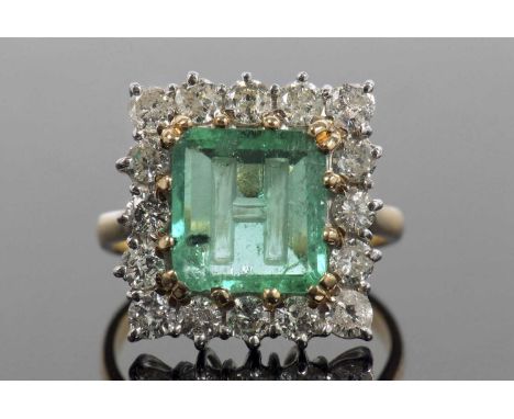 An emerald and diamond ring, the emerald engraved with the letter 'H', 10.19 x 9.62 x 3.15mm, multi claw set and raised withi