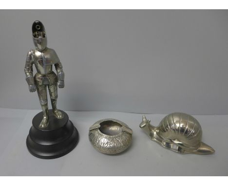 A novelty table lighter in the form of a Knight, a novelty ashtray in the form of a snail and a white metal ashtray 