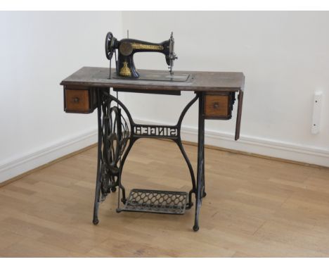 A Singer treadle sewing machine, model number F3456490, c1900, mounted on a hinged oak platform with central drawer flanked b