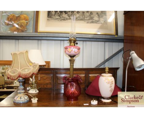A Victorian brass Corinthian column oil lamp with painted opaque reservoir and ruby tinted frilled shade 