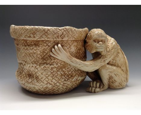 A Bretby Ivorine novelty planter, modelled with a chimp clutching the planter, glazed throughout in tones of ivory and light 