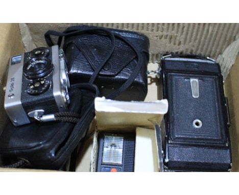 		A Rollei 35 compact camera with flash gun and three other cameras