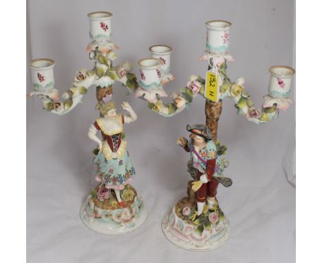 		A pair of Voigt Bros. Sitzendorf figural three light candelabra modelled as a lady and gentleman in gaily coloured attire s