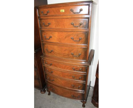 		A reproduction walnut bow fronted chest with eight long drawers on cabriole legs. 26' wide