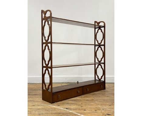 An Edwardian mahogany hanging wall shelf each tier united by pierced fret-carved panel end supports, with two drawers to base