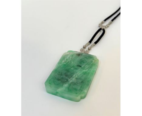 A striking diamond and jadeite pendant in the Art Deco taste, c.1930, the rectangular jadeite jade plaque carved in relief wi