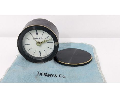 A Tiffany & Co. travel alarm clock in a gunmetal coloured case with rotating cover, numbered 12570Location: 