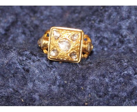 A precious yellow metal and diamond ring, the stepped square mount set five rose cut diamonds, with shaped and pierced should