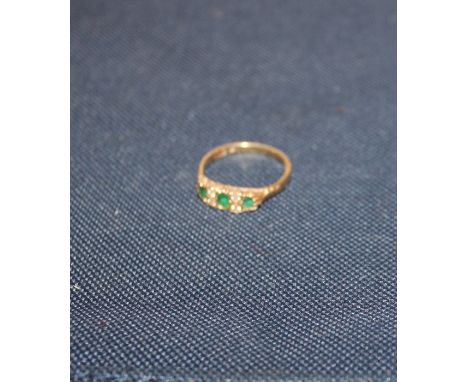 An 18ct. yellow gold, emerald and diamond ring,&nbsp;set oval cut emerald to centre with single round cut emerald to either s