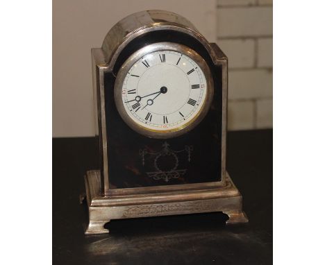 A silver cased and tortoiseshell mounted mantle clock, c.1920, the arched top silver rectangular case raised upon bracket fee