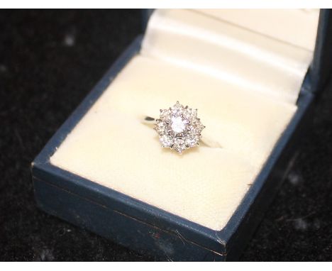 An 18ct. white gold diamond cluster ring, set round brilliant cut diamond to raised centre bordered by eight further round br