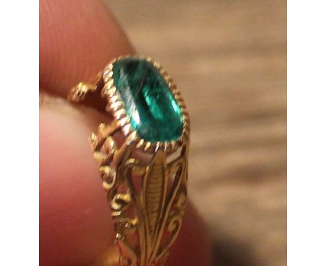 A 19th century yellow metal and emerald ring, set oval cut emerald to centre, with pierced scroll work gallery and shoulders,