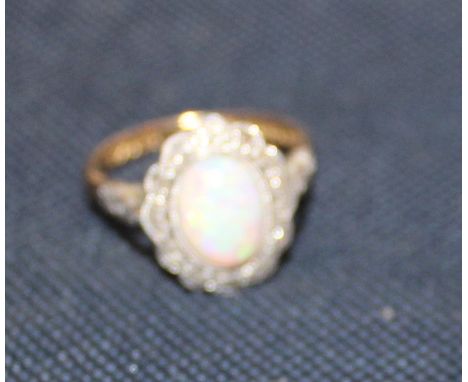 An 18ct. gold, diamond and opal ring, set oval cabochon opal surrounded by border of diamond chips, with engraved shoulders, 