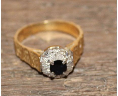 An 18ct. gold, sapphire and diamond dress ring,&nbsp;four claw set central round cut sapphire, bordered by eight round cut di