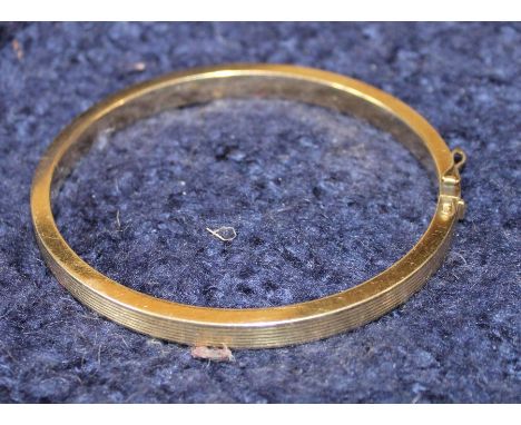 A 14ct. yellow gold hinged bangle, with ribbed banding, stamped "585", (24.9g)