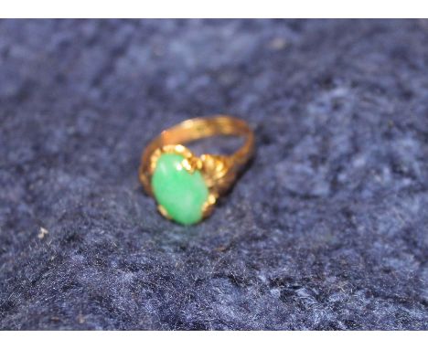 A precious yellow metal and jadeite ring,&nbsp;possibly Chinese, set oval cabochon untreated green jadeite, with applied and 