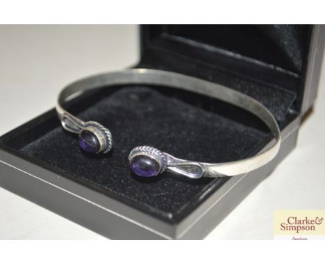 A white metal bangle set amethyst coloured stones