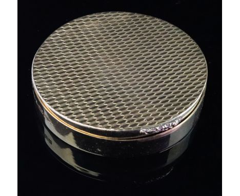 A circular 9ct gold compact, W.H.M., Birmingham 1967, the flush hinged cover and base engine turned, having a foliate cast th