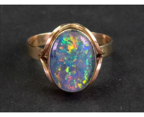 A gold mounted oval opal doublet solitaire ring, decorated with scrolled shoulders, detailed 9 CT, 3.3g gross, ring size S.