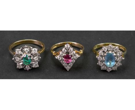 A collection of three gem set rings comprising: an 18ct gold aquamarine and diamond cluster ring, an 18ct gold emerald and di