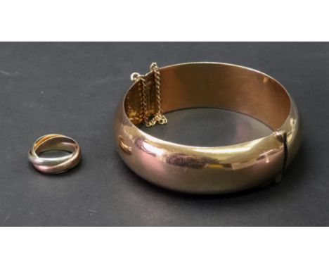 A pink precious metal hollow hinged bangle of oval design, complete with safety chain, (presumed 9ct rose gold untested); and