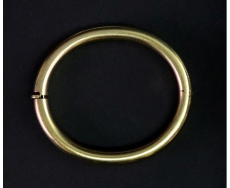 A yellow gold hollow hinged bangle of rounded oval design, stamped 750, 34.10g gross approximately.