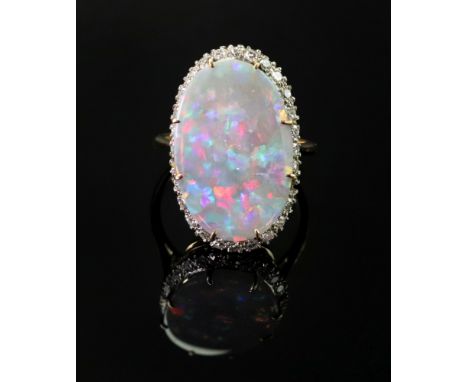 An opal and diamond oval cluster ring, claw set with the oval opal in a surround of circular cut diamonds (one diamond lackin