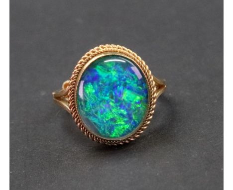 A 9ct gold opal triplet ring, F&amp;R.B. Birmingham 1971, the oval collet set stone in a double ropetwist bordered mount, rin