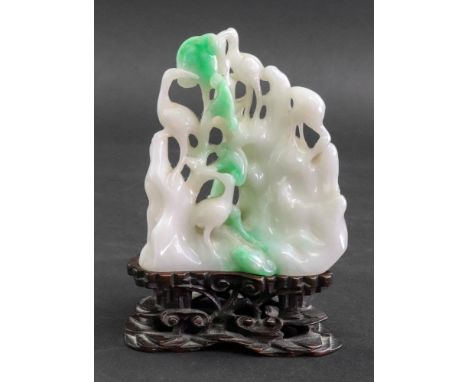 A Chinese jade carving, 20th Century, of four storks amongst trees and rockwork, 8cm high, carved rosewood stand, 11cm high o