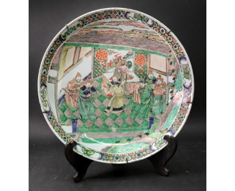 A Chinese famille verte charger, Kangxi, painted with a court scene, within a brocaded border interspaced by panels of scroll