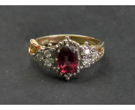 A gold, purplish pink tourmaline and diamond ring, the oval cut tourmaline claw set between a trefoil of diamonds to a decora