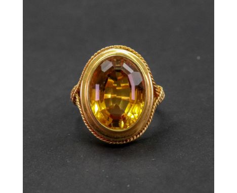 An 18ct gold citrine ring, S &amp; Co, Birmingham 1971, the collet set oval cut stone in a triple ropetwist bordered mount, r