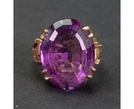 A gold ring, claw set with a large oval cut amethyst between split shoulders, detailed 9 CT, 8.2g gross, ring size L.